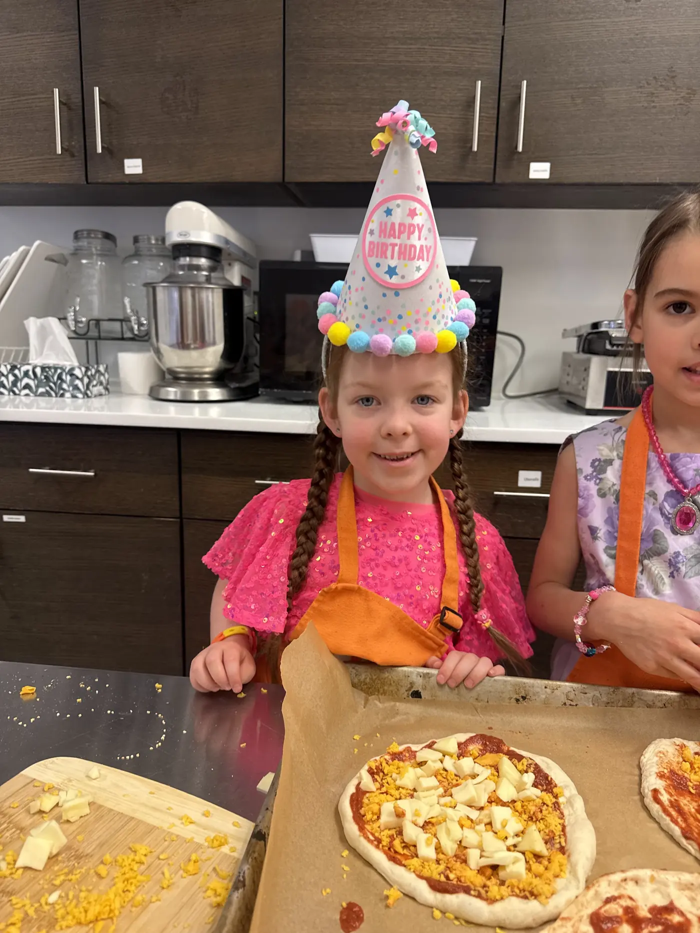 Child in a party hat making pizza at a Cookiddoo kids birthday party in Ottawa