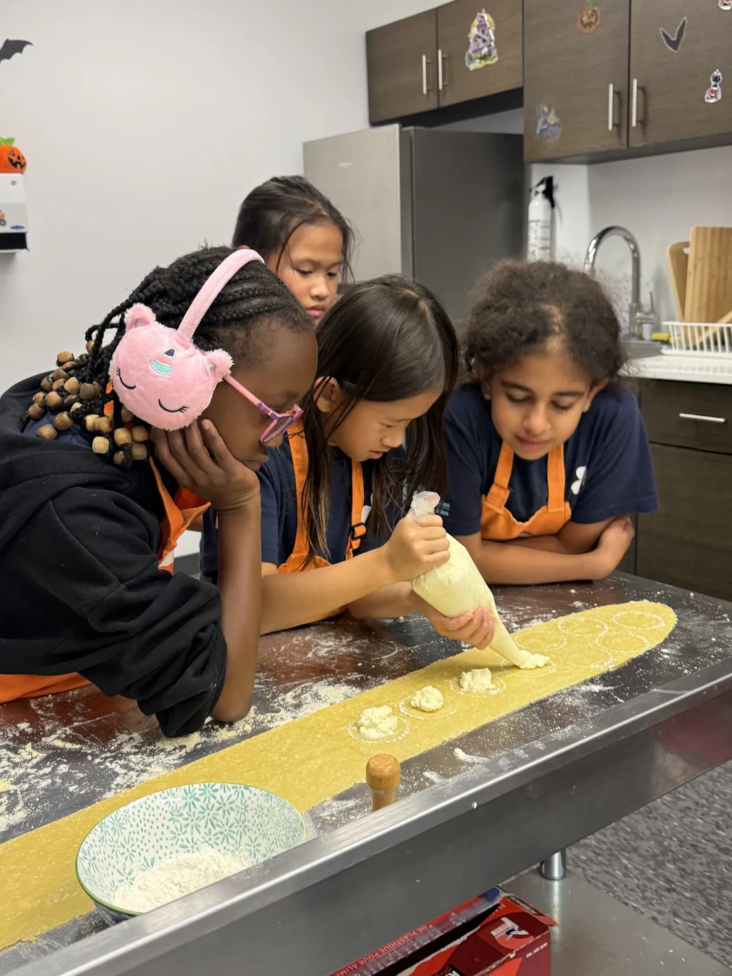 Kids piping filling into fresh ravioli at a Cookiddoo cooking class