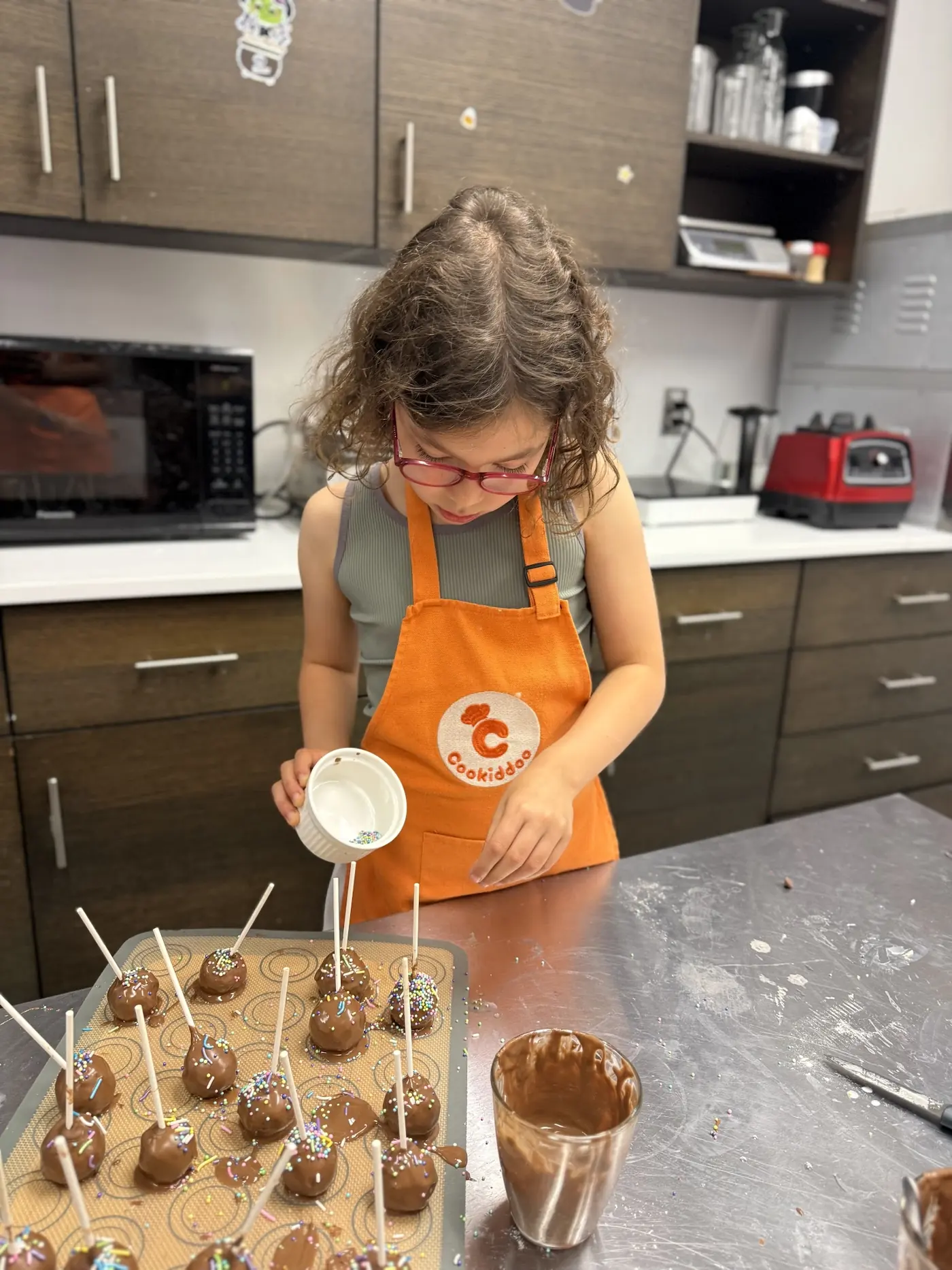 Child decorating colourful cake pops, a culinary gift idea from Cookiddoo Ottawa