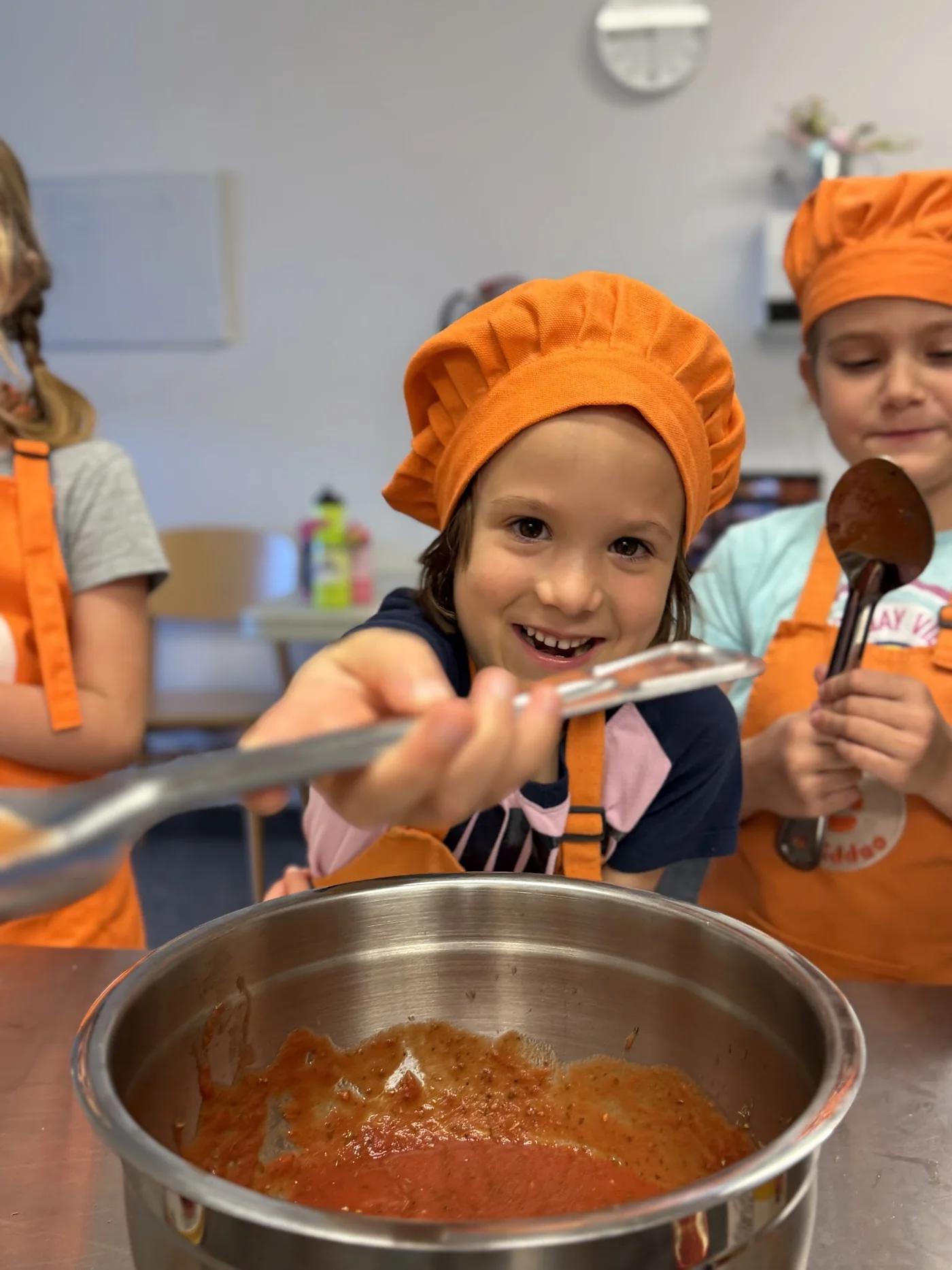 Ребёнок помешивает томатный соус на детском кулинарном занятии Cookiddoo в Kanata, Ottawa