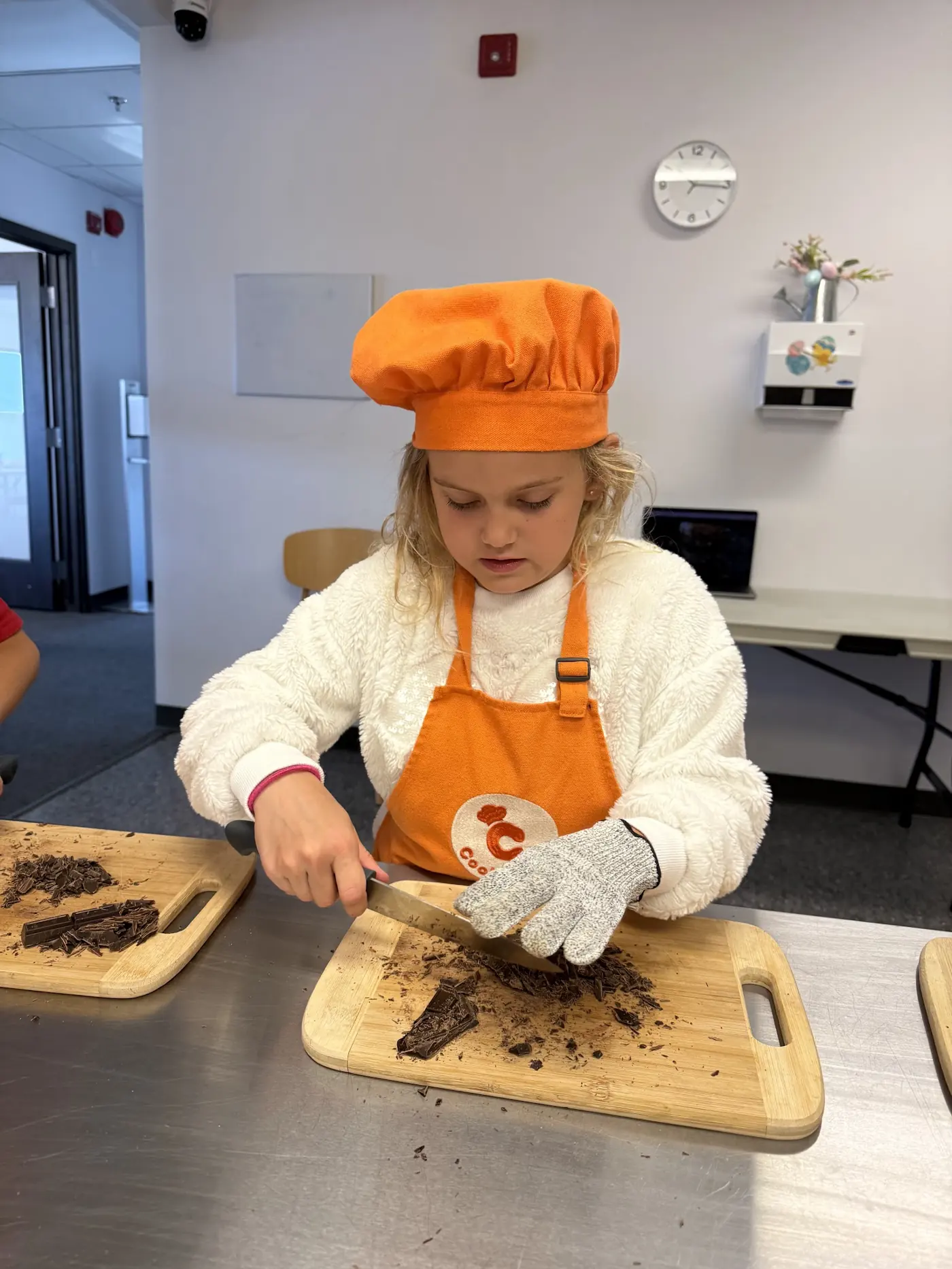Young chef carefully chopping chocolate during a structured Cookiddoo junior chef course in Ottawa