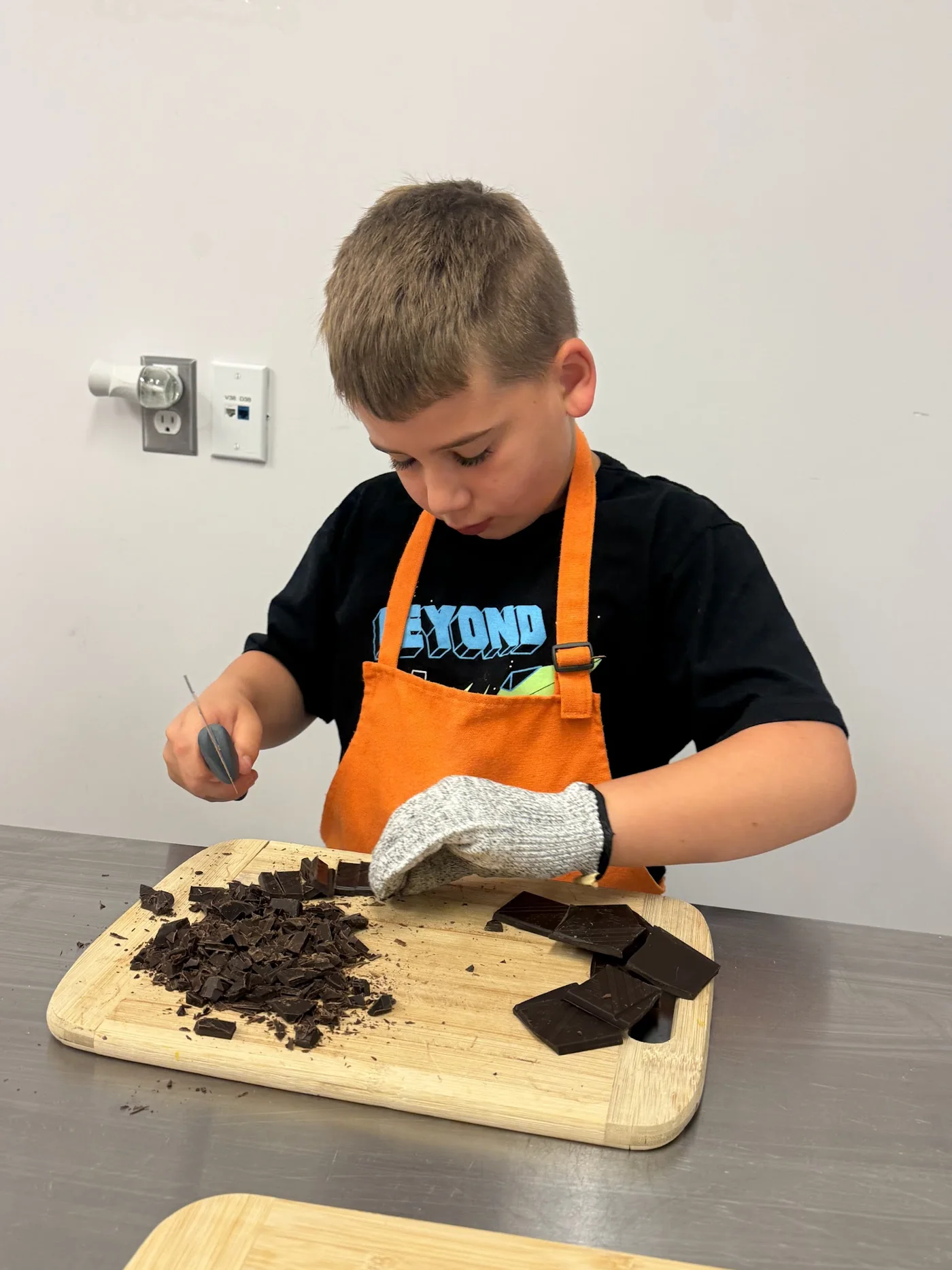 Child using kitchen tools safely with gloves at Cookiddoo in Ottawa